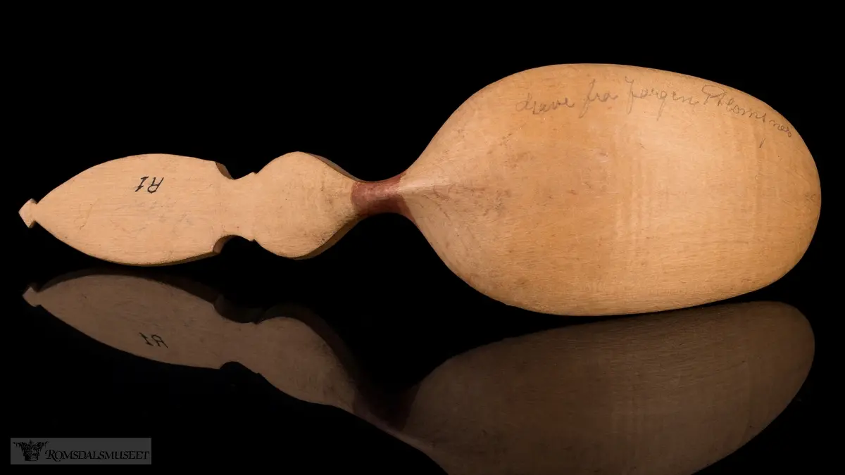 Liljemønster på håndtaket, og rankemønster og røde prikker på selve skjeen.