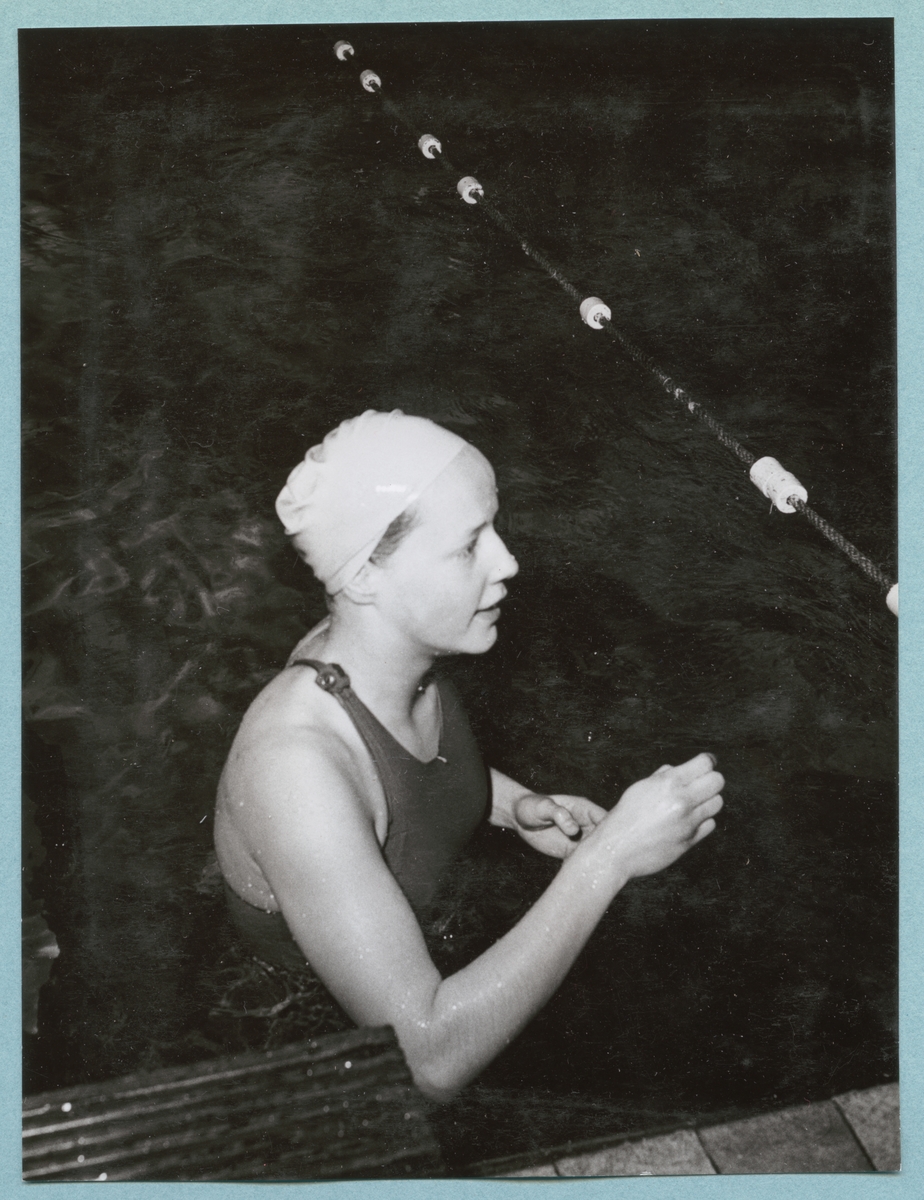 En kvinnlig simmare, klädd i baddräkt och badmössa, står i simbassängen tillhörande Sparres simhall. Fotot är daterat till 15-3-1952.