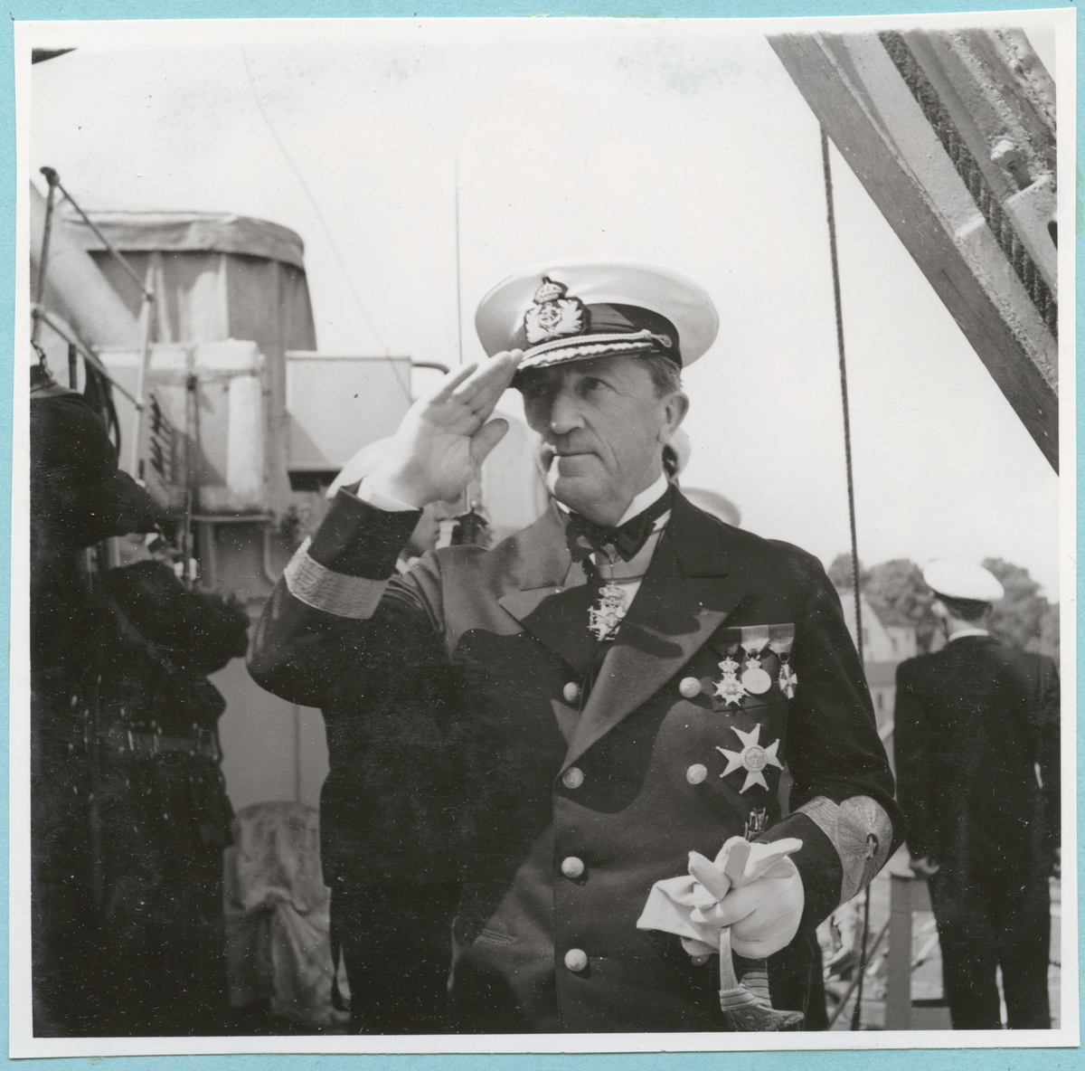 Befälhavande Amiral Samuelson besvarar Kommandør Paulsons besök ombord på Holger Danske. Från Danska och Norska örlogsbesöken den 29/6 - 4/7 1951. Konteramiral Samuelsson är klädd i unifrom med flera medaljer på bröstet. På bilden gör han honör.