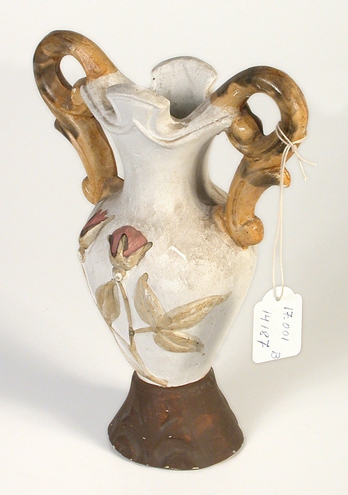 Par, vita med brun fot, greparna en på vardera sidan (motstående), gula och grå-brokiga samt på själva vasen en blomkvist (löv och tvenne blommor) på ena sidan, till färgen gulgrön och violett.