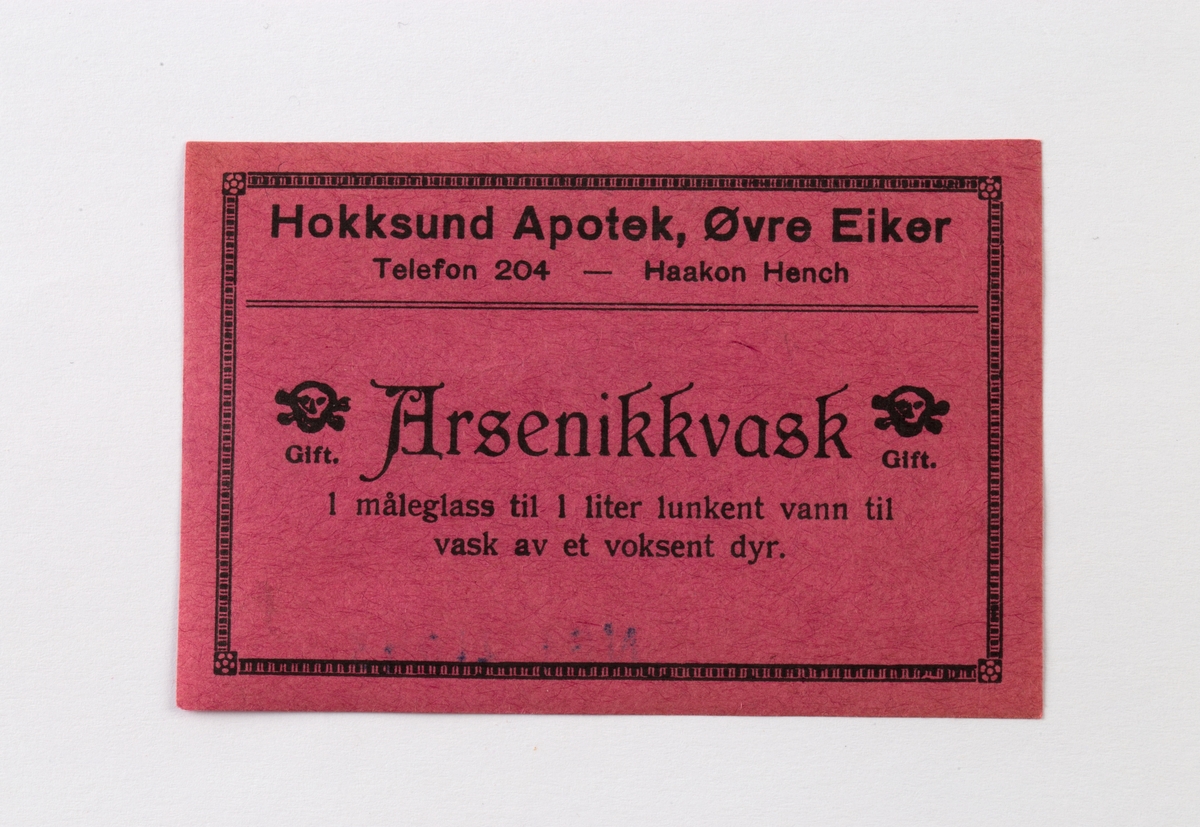 Rød etikett med sort skrift for Arsenikkvask. To giftemblemer.