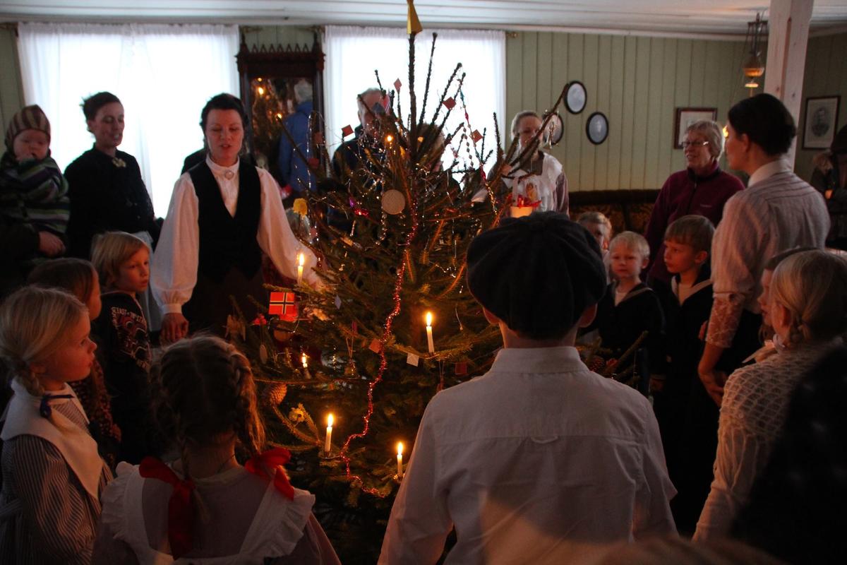 Juletrefest i storstua i Gjersøyenbygningen på Odalstunet under Jul i stuene. I den innerste ringen står Berit Storbråten med ansiktet mot kamera og bak henne Mona Holm.