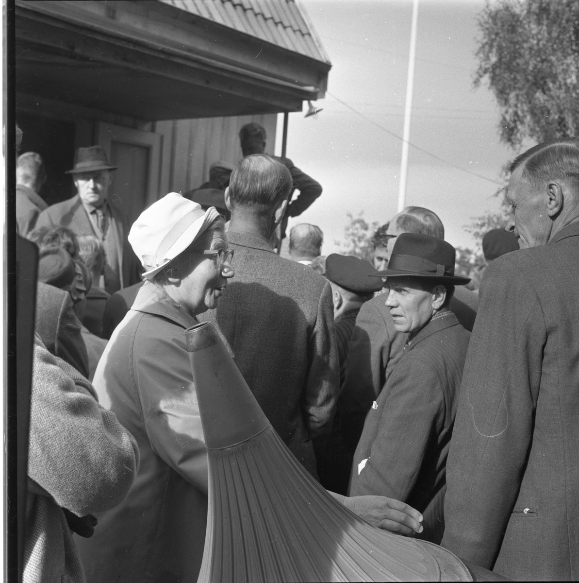 En okänd folksamling, möjligen auktion. Mannen i hatt som vänder sig mot kameran är Roy Andersson i Reaby. Damen i vit hatt är Anna Andersson och till höger står Karl Andersson.