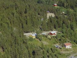 Øyer, Tretten. Rødbrunt, enetasjes hus med balkong og kjøkke