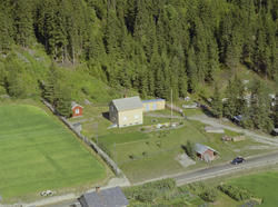 Øyer, Tretten. Gult enetasjes hus med hvit grunnmur, to uthu