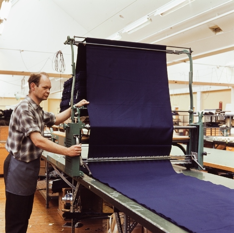 Martin Kristian Holmen, en ansatt i konfeksjonsfabrikken til Jonas Øglænd Sandnes legger opp stoff for tilskjæring med oppleggsmaskin.