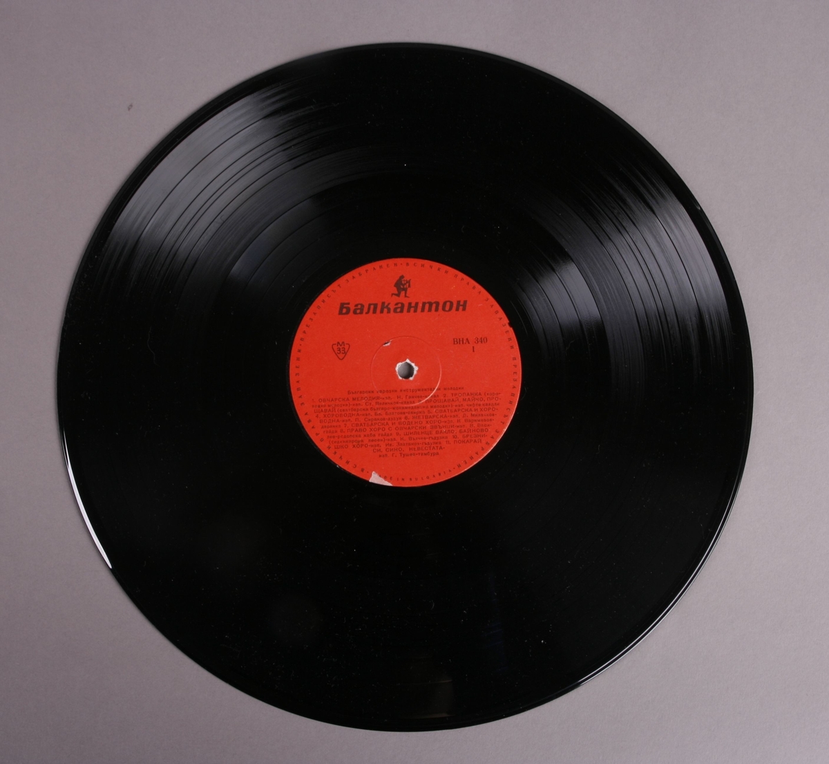 Grammofonplate i svart vinyl med plateomslag av papir. Platen ligger i en Plastlomme. Påskrift med blyant på baksiden av plateomslaget (se bilde).