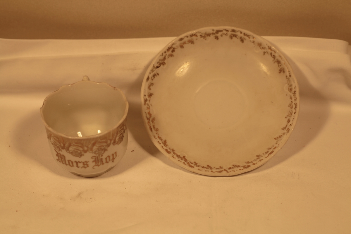 Kopp og skål i hvit porselen med gulldekor. Innskrift: Mors kopp. Gammelt nr: 2565c