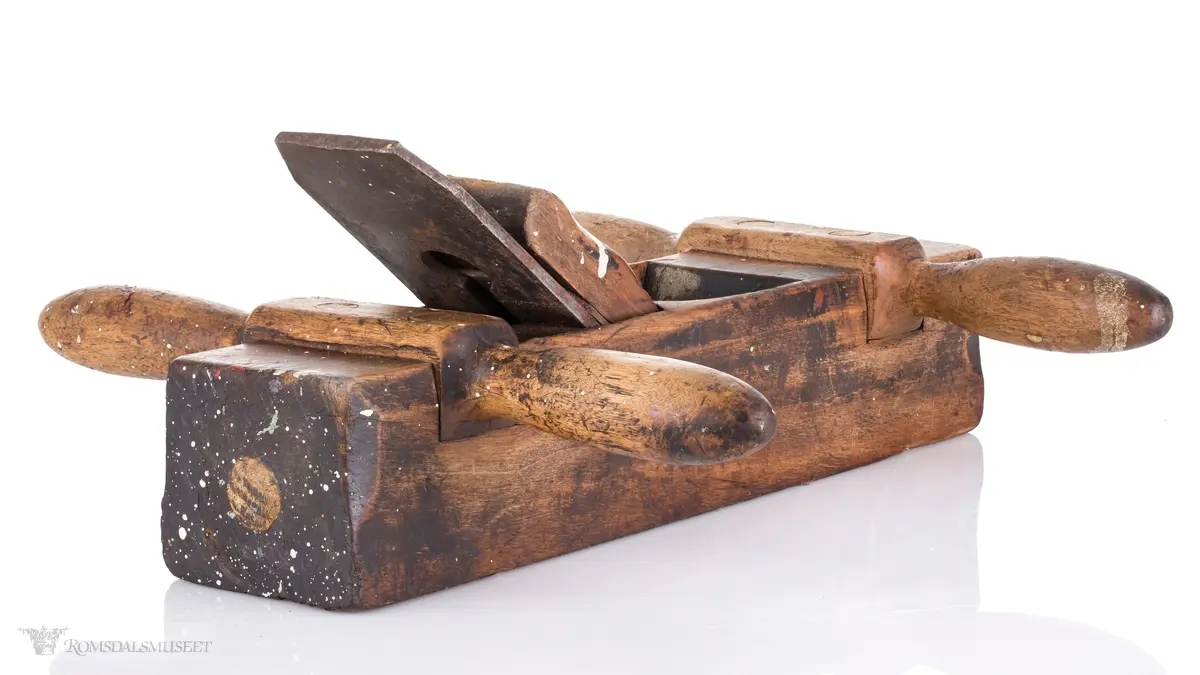 Oksehøvel i tre med rektangulær høvelstokk. Sponhus på toppen med høveljern med klaff og kile. Knekt av tre slått inn i bakkant.