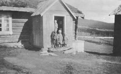 Barn i døråpning på bolighus. Oskar, Anna, Marit, bak Einar 
