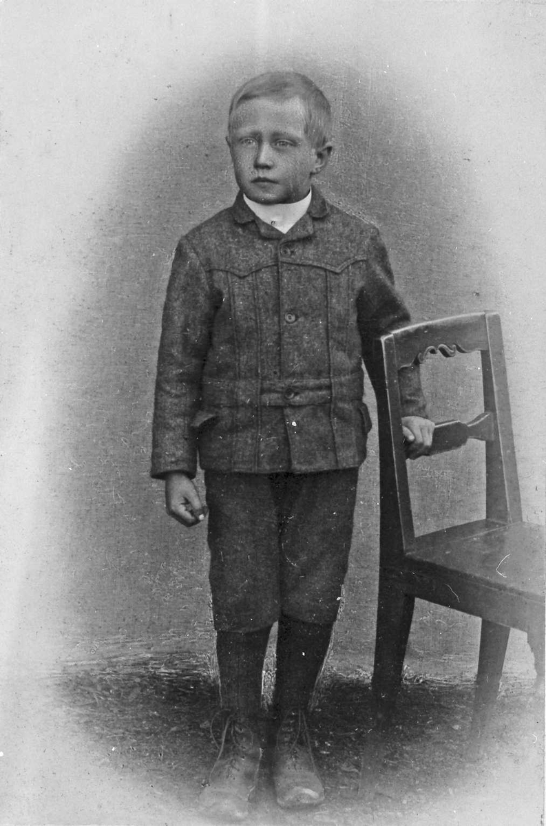 Portrett av en liten gutt med stol. Oskar Frankmo. 