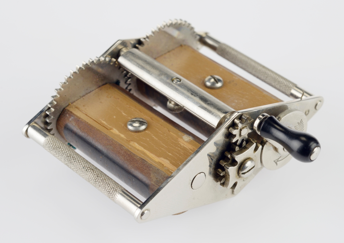 Roterende slipere i tre med sveiv. Ligger i en svart plast eske med lilla stoff på innsiden med bruksanvisning.