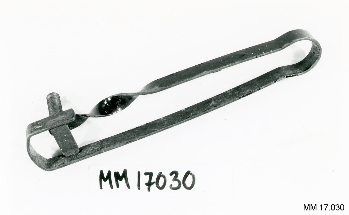 Tändare av böjt järnband ( B = 9 mm ), i ena änden svängd och sammanhållen av räfflat band. I andra änden vriden två varv samt längst ut försedd med gängad hylsa som ligger mot det räfflade bandet. Inuti hylsan sitter ett stift för gnistbildningen. Målad i svart. Stämpel " BeBe-Funktewel ".