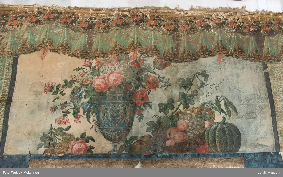 |Tapeten er påmalt tapetborder og brystning. Fra Hovland gård i Larvik.
Den øverste, brede borden: Gerlander/draperi med blomsterranker.
Den nederste, smalere borden: Tekstilbord med blomster. Øver døren til høyre: Stillebenmotiv med blomster og frukt.