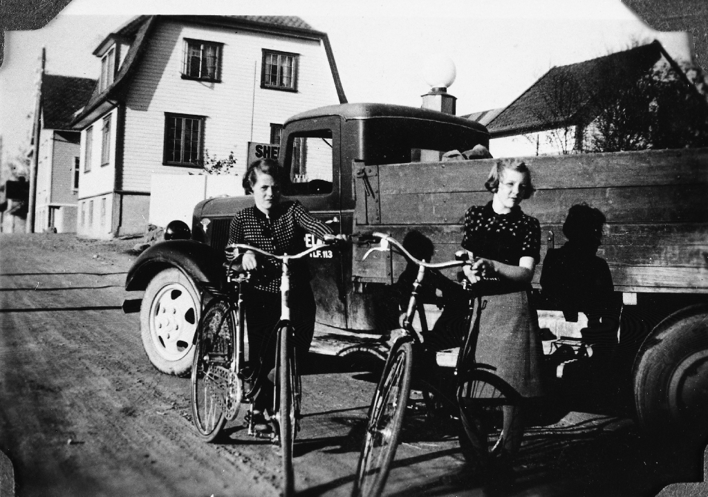 Bjørg Hareland g. Fylling (3.12.1927 - ) og Ingrid Hareland g. Borge (11.7.1926 - ) med nye syklar i 1938. Bilen tilhøyrer far deira, Charles Hareland (31.10.1896 - 15.5.1979), og huset i bakgrunnen tilhøyrde Torvald Våland.