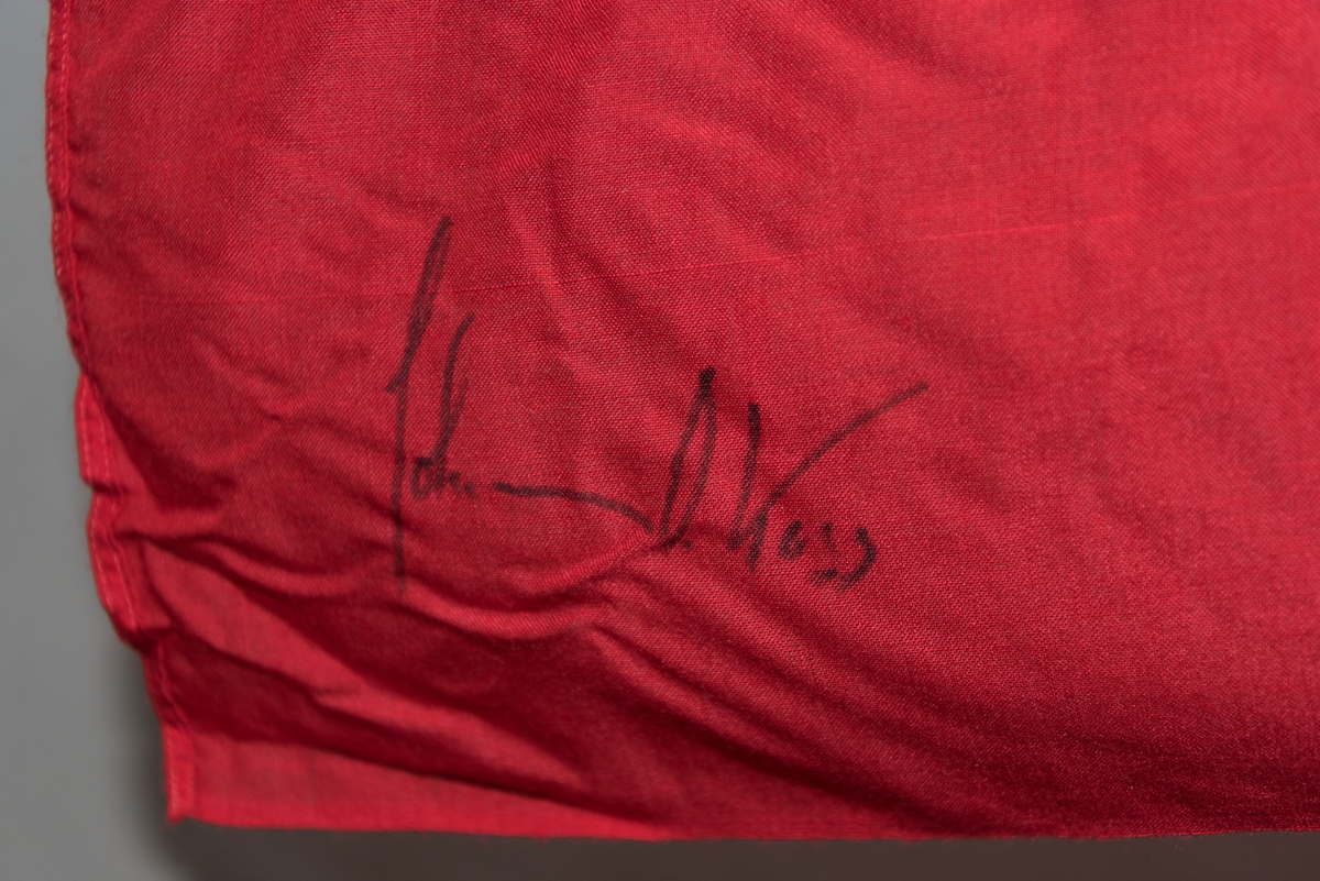 Norsk flagg med signatur av Johan Olav Koss. Flagget ligger en kartonghylse.