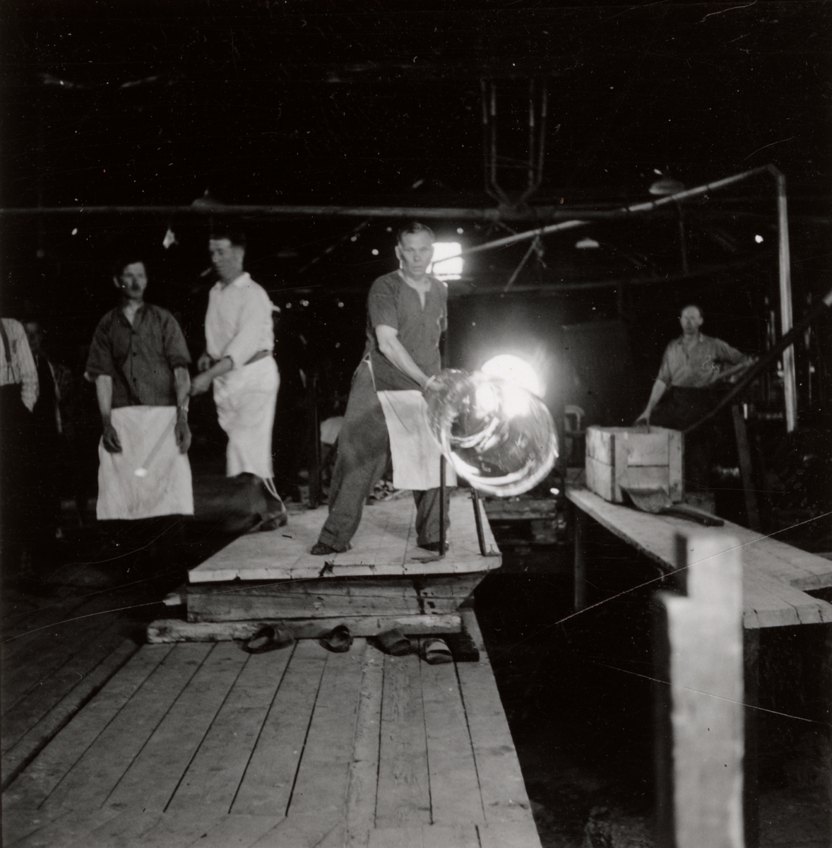 Gullaskrufs Glasbruk, Småland.
Fönsterglasblåsning i samband med filmning den 12 juni 1941. Valsen färdig att bära ned på knäckan.