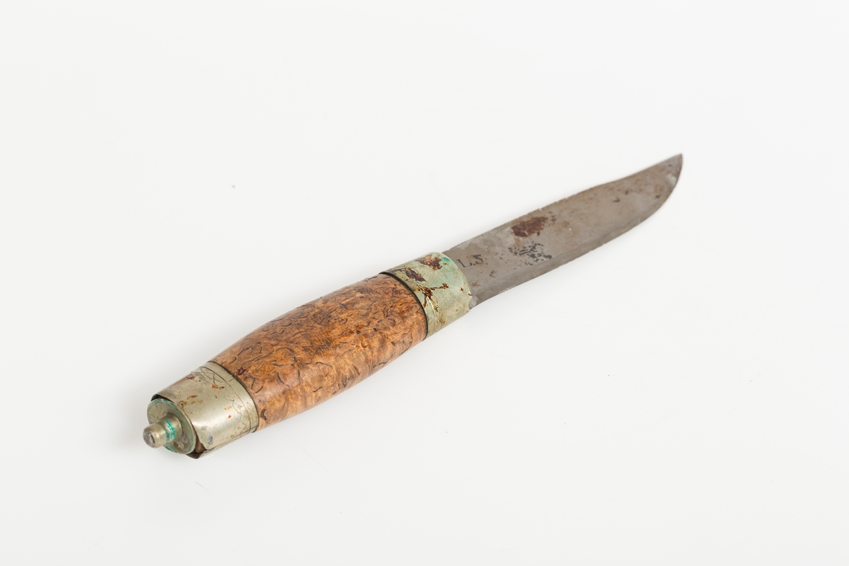 Tollekniv av tradisjonell norsk/nordisk type. Håndsmidd laminert blad med nedsvingt spiss og to dekorhakk innerst på ryggen. Store bruksspor med slagmerker på rygg og hakk i bladet. Store rustpartier. Gjennomgående ulimt tange med tapp til slirestropp. Skaft i valbjørk. Håndlagde loddede holker, mest sansynlig av nysølv (legering av messing, kobber og zink), med trambulerte dekorborder. Bladholken er løs. På toppholken har loddingen løsnet helt slik at toppen er totalt adskilt fra sidedelen av holken. 

Bladet er stemplet L.S. I følge Norsk knivforening kan dette være
Skålbø, Lars Sondresen 1850-1940, NO-01547, Tinn / Telemark
Kategori: Smed, Kjennetegn: Stemplet  LS (skjønnskrift), LS og L.S. TINN. på knivbladene.