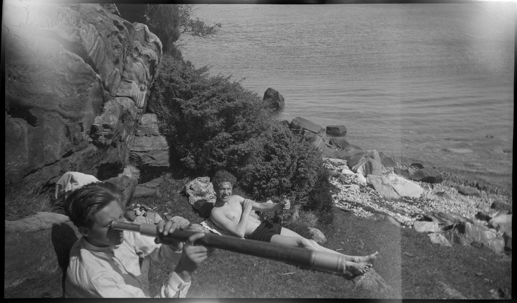 Harald Bergsaker, Ottar Roaldsøy, L. Fosse og Lindtner på den søndre enden av øya Hidle, øst for Stavanger. De er på kanten av et stup og hviler i gresset under stupet. En av dem ser utover sjøen med kikkert. Seilbåten "Vilja ligger i bakgrunnen.