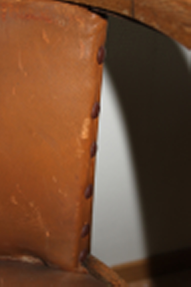 Møteromstol/kontorstol med armlener samt buet rygg. 4 ben. Metallbeslag under armlener. Brunt skinn i rygg og sete. Stolen er lakket med klar lakk. Originalt møbel innkjøpt til det nye Statsarkivet i Kristiansand i 1935.