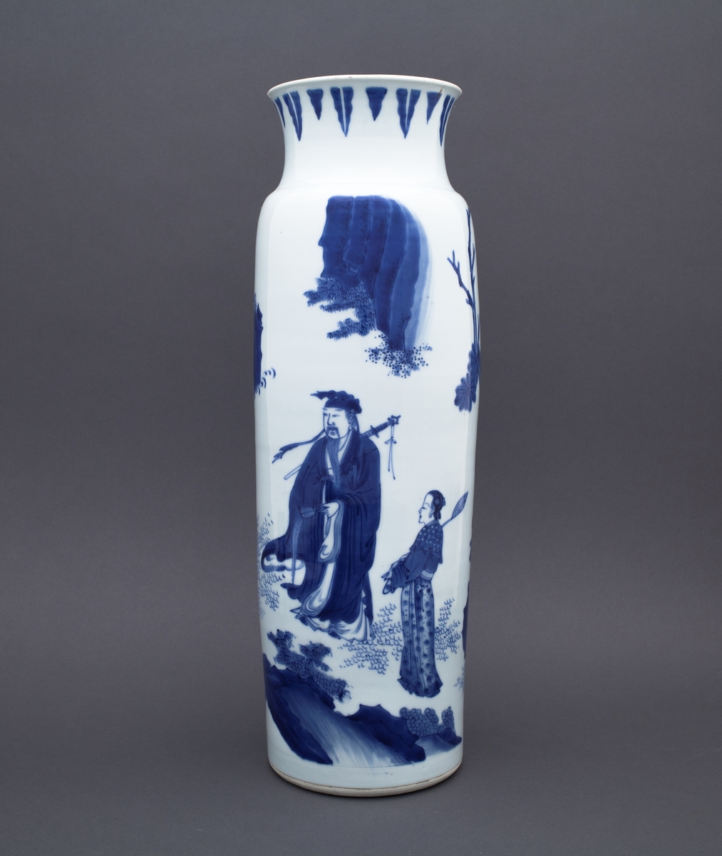 Tre mennesker står foran et stort tre. I bakgrunnen ser vi to fjelltopper. En mann står med foldete hender foran en annen mannsfigur. Han har skjegg, et sverd på ryggen og han holder i en vifte. Ved siden av mannsfiguren med sverd og vifte finner vi en kvinneskikkelse, som også holder i en vifte.