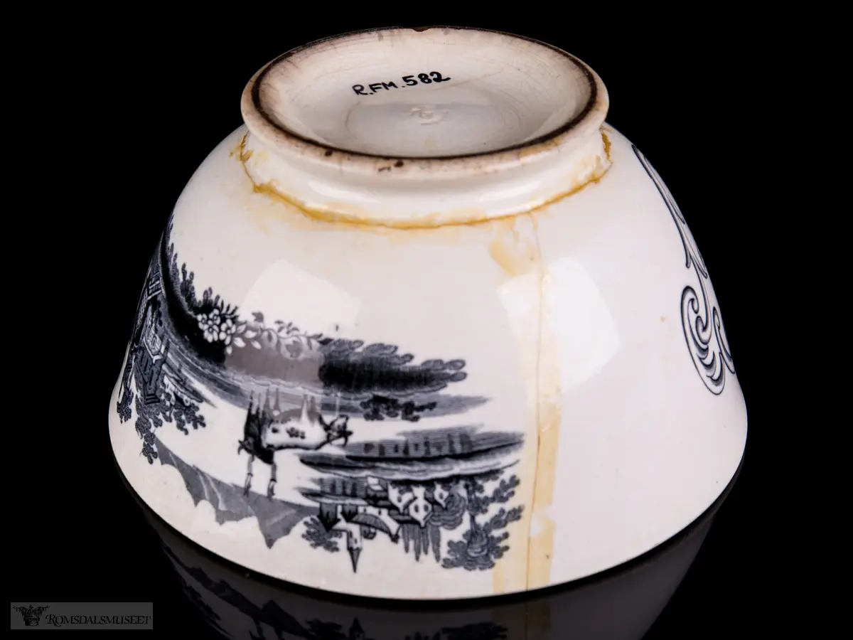 Innvendig et landskap med en klosterruin, hus og vegetasjon med vann rundt, og to kyr i forkant. På bollens sider er det et motiv med bebyggelse på en øy i en innsjø med seilbåter på vannet, fjell i bakgrunnen, og en borg eller landsby og to kyr i forgrunnen. Akantusranker rundt påskriften.