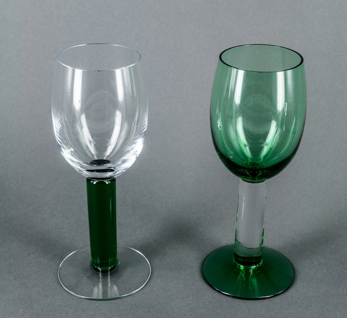 Vitvinsglas, prov till "Nobelservisen". Avhugget äggformad kupa samt fot av ofärgat glas. Högt, cylindriskt ben av grönt glas. Design Gunnar Cyrén för Orrefors Glasbruk.