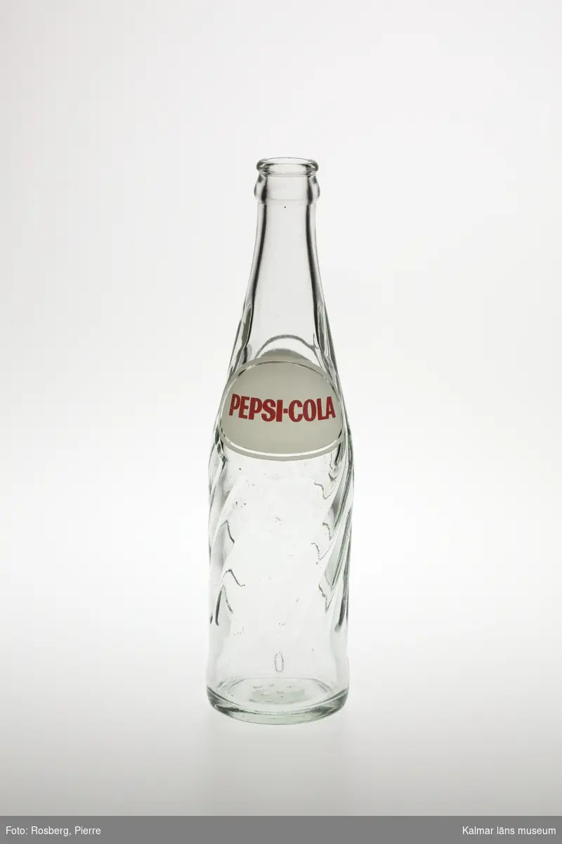 KLM 46156:3 Flaska, av glas, klarglas, ofärgad. Nedre halvan av flaskan spiralvridet randat i glaset. Av märket Pepsi-Cola. Etikett, tryckt direkt på flaskan röd text på vit botten, övrig information gjuten i glaset. Text med färg, på sidan: Pepsi-Cola, Pepsi-Cola reg. varumärke. I flaskans botten gjutet i glaset: 804 PLM 7.
