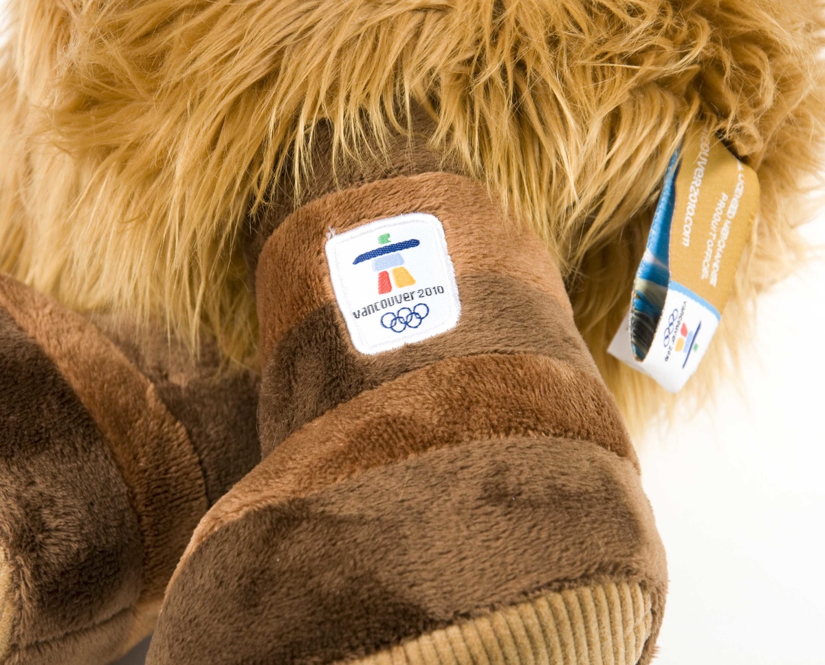 Brun figur av Quatchi; en av maskotene for de olympiske vinterleker i Vancouver i 2010. Figuren har blå og hvit ørevarmer. På figuren er det emblem for de olympiske vitenterleker i Vancouver. 