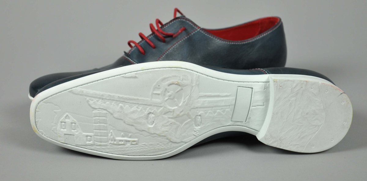 Et par blå skinn herresko i str.44,røde skolisser,røde og hvite sømmer .
Traktor-logoen påtrykt i hvitt på begge skoene.