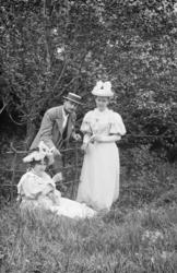 Gruppe, en mann og en kvinne står, en kvinne sitter i gresse