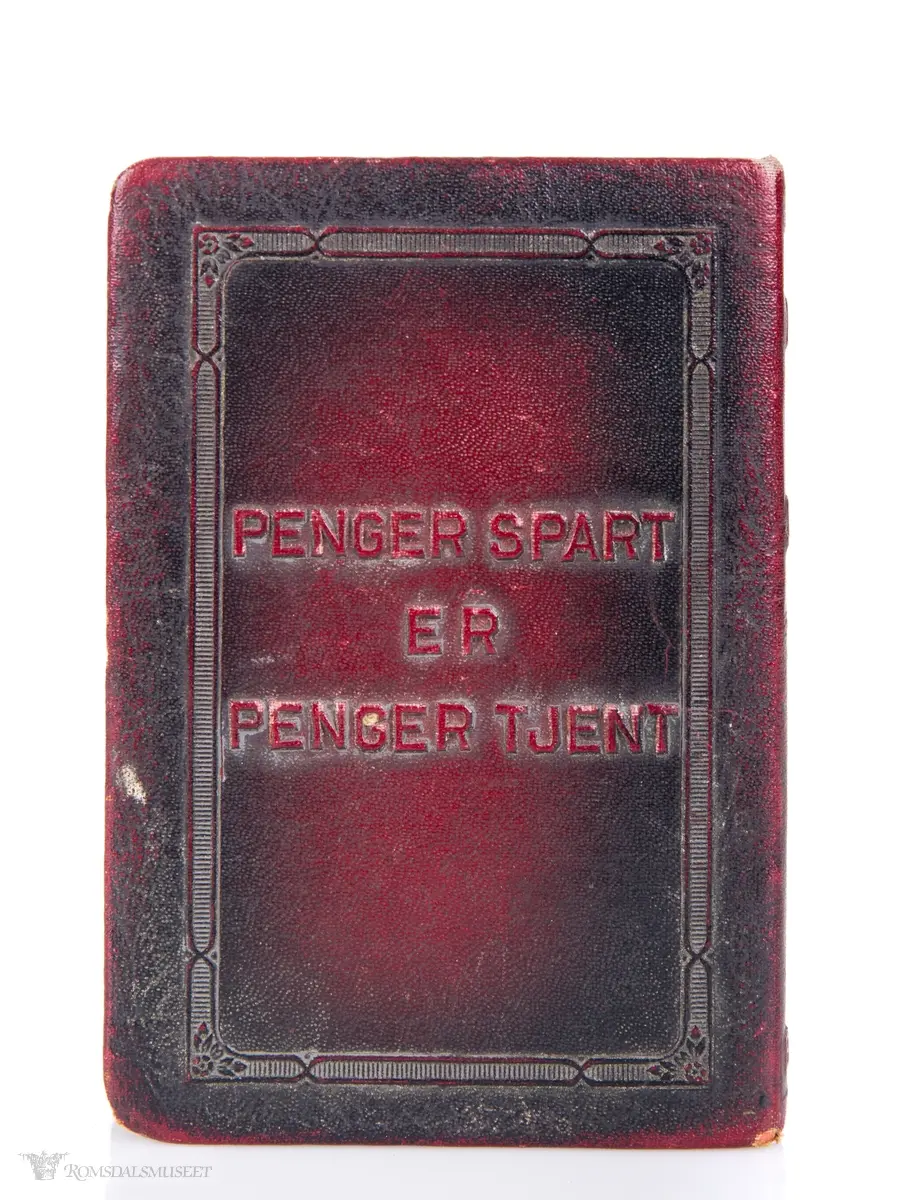 En sparebøsse i messing, formet som en liten bok, kledd i skinnimmitasjon.
