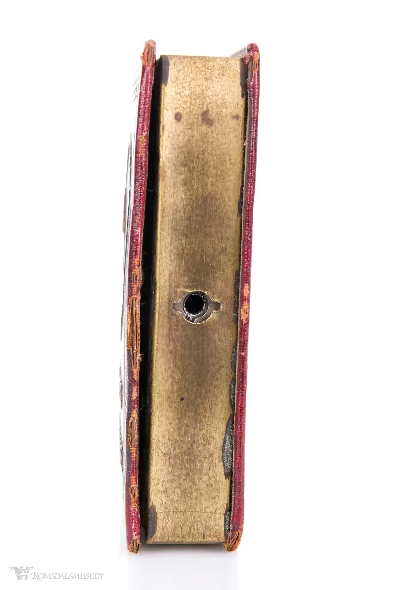 En sparebøsse i messing, formet som en liten bok, kledd i skinnimmitasjon.