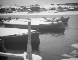 Lektere med hus ved elvebredden i bakgrunnen