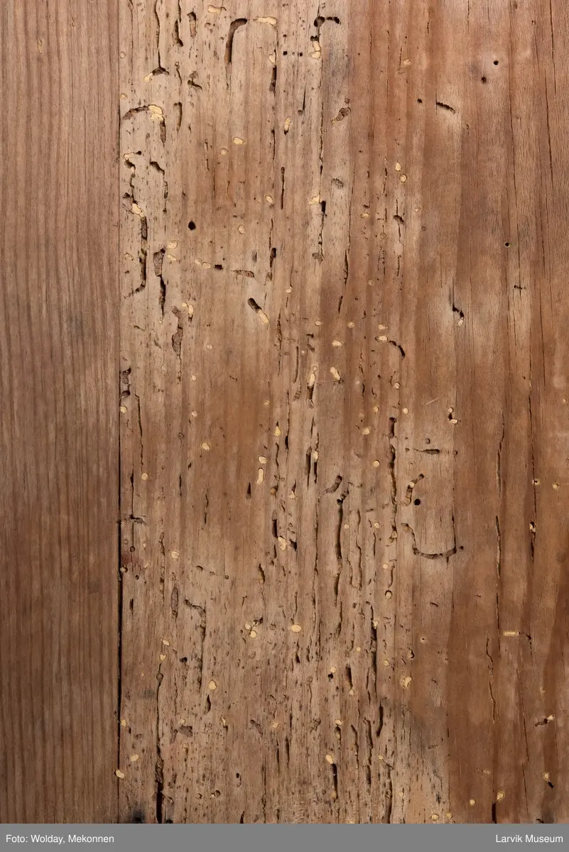 Kommoden har 4 skuffer. 2 beslag for å dra ut, 1 beslag for nøkkelhull, messing. Utskåret dekor under øvre pyntelist "tanngard" rundt på 3 kanter. Øvre skuff utskåret med bølgebånd med rett linje som bryter bølgene. Utskjæring kun i front. To av kommodens hjørner har utskåret søyle. Håndtak på kortsidene for å bære i.