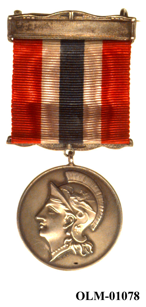 32 forskjellige medaljer og merker i ramme.
Bilde 7 er deltdagermerke fra Amsterdam 1928.
Bilde 18 og 19 er deltagermedalje fra Amsterdam 1928.
Bilde 20 og 21 er sølvmedaljen fra Antwerpen 1920.
Bilde 26 og 27 av bronsemedaljen fra Paris 1924.
Bilde 39 og 40 minnemedaljen fra Antwerpen 1920.