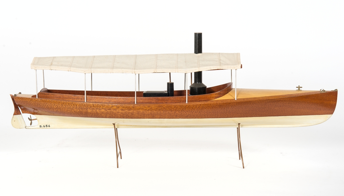 Fartygsmodell av ångdriven båtmodell. Halvdäckad förut, Akterut och midskepps maskin- och sittrum täckt med solsegel. Fasta skrån av koppartråd. "Ljungströms ångmotor(!)båt"