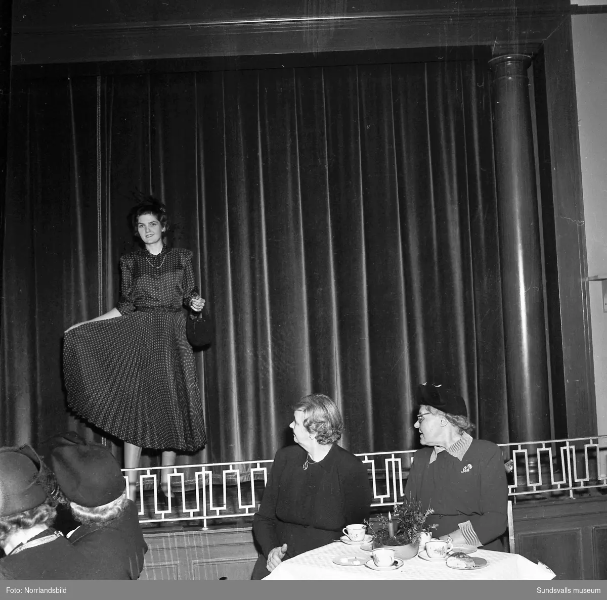 Lottakåren arrangerade mannekänguppvisning i läroverkets aula i Timrå. På första bilden visar Svea Backlung en svart klänning i kravattsiden för Ester Larsson och Märta Dahlström.