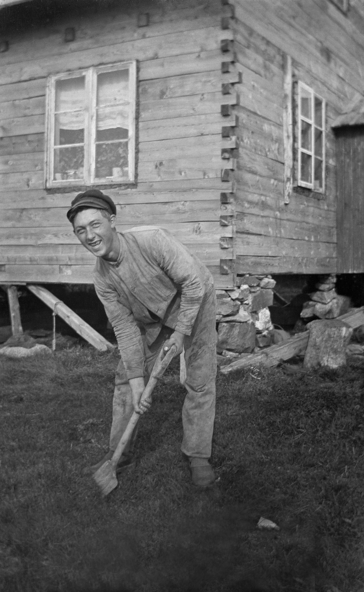 Mann som graver med spade foran hus.