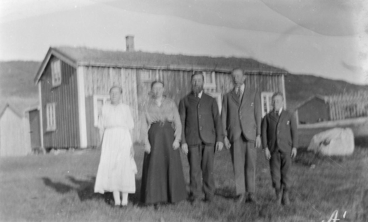 Tre menn og to kvinner står foran hus.
