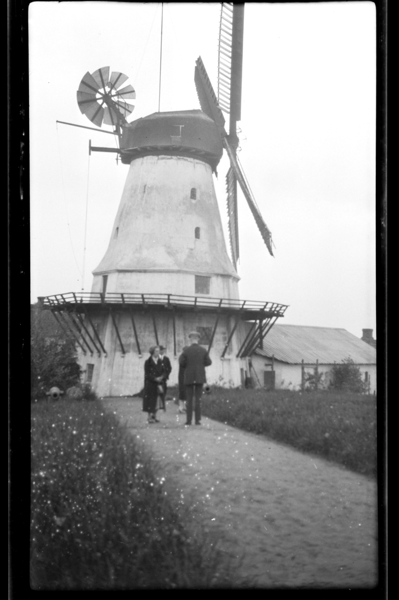 Fire ukjente personer foran en vindmølle. Fotografert 1927.