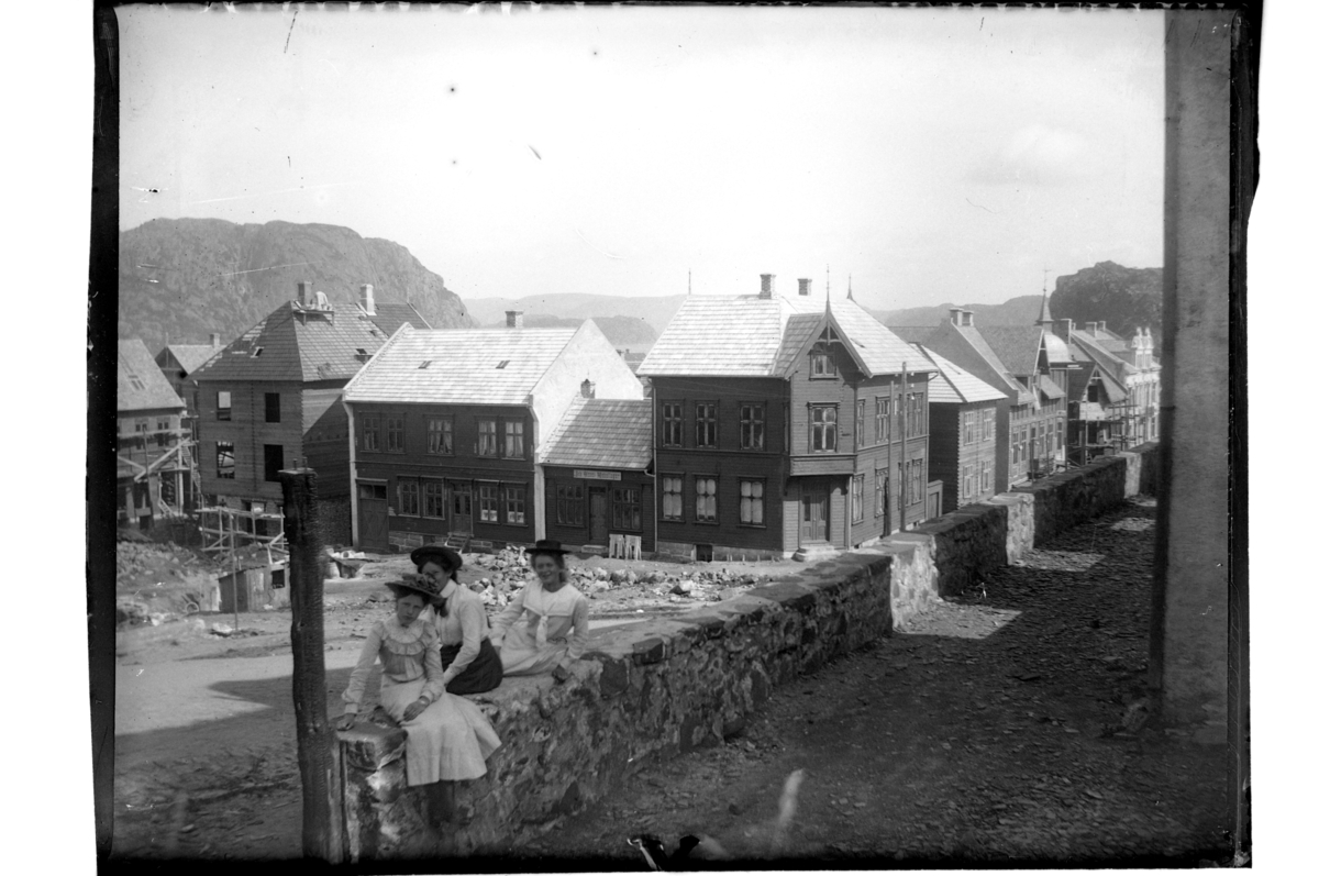Tre unge jenter foran kirkeruinen, etter bybrannen 1901, mot Nytorvet i Farsund. Fra venstre ukjent, Tiljen Thurmann-Andersen og Plata Atlanta Buch. Fotografert 1903.