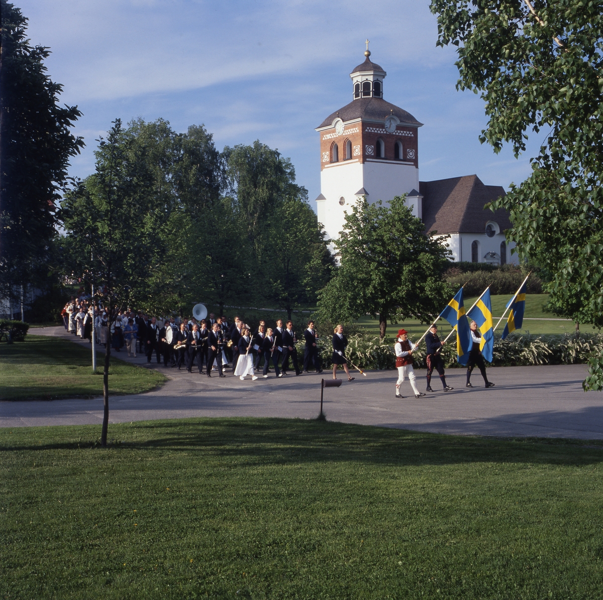 Nationaldagen i Bollnäs 6 juni 2001. Fanbärare, musikanter och andra deltagare tågar från kyrkan.