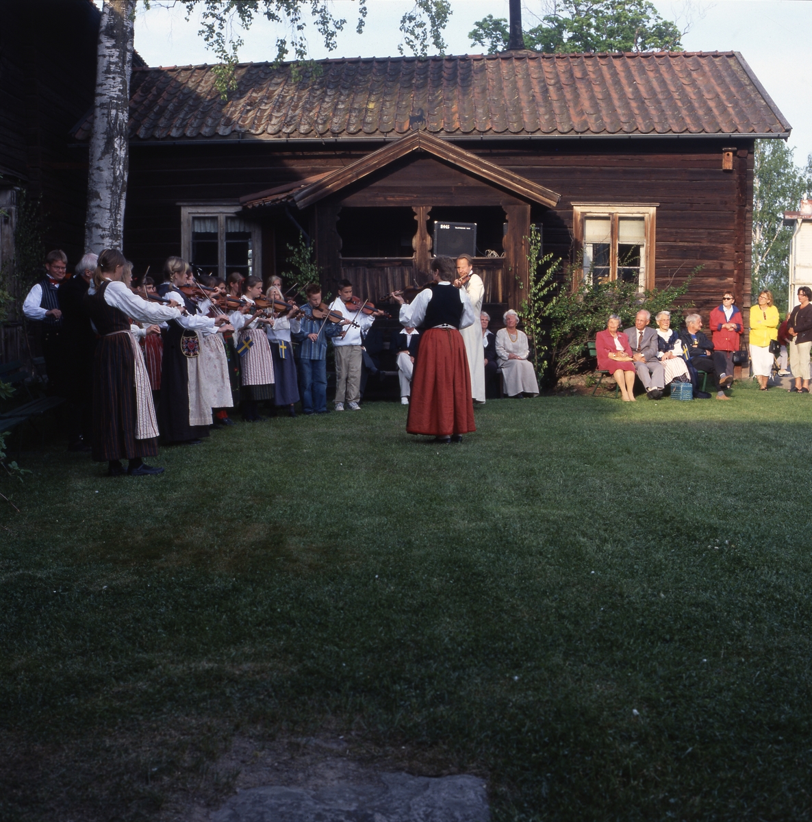 Nationaldagen i Bollnäs 6 juni 2001. Spelmän och publik utanför en gammal timrad gård.