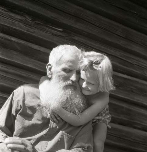 Liten flicka kramar en gammal man med yvigt vitt skägg.