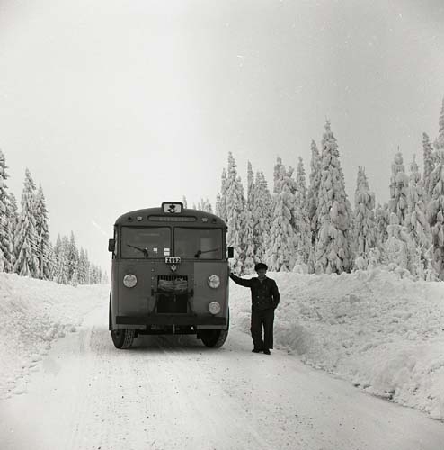 En chaufför står intill sin buss i ett snöigt landskap i Hammerdal, Jämtland, 19 februari 1955.