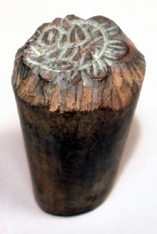 Tryckstock för mönstertryck i trä med utskuret mönster i form av en blomma. Rester av grön färg.