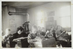 Elever jobber hardt med leksene inne i skolestua. Bilde datert til starten på 1900-tallet.