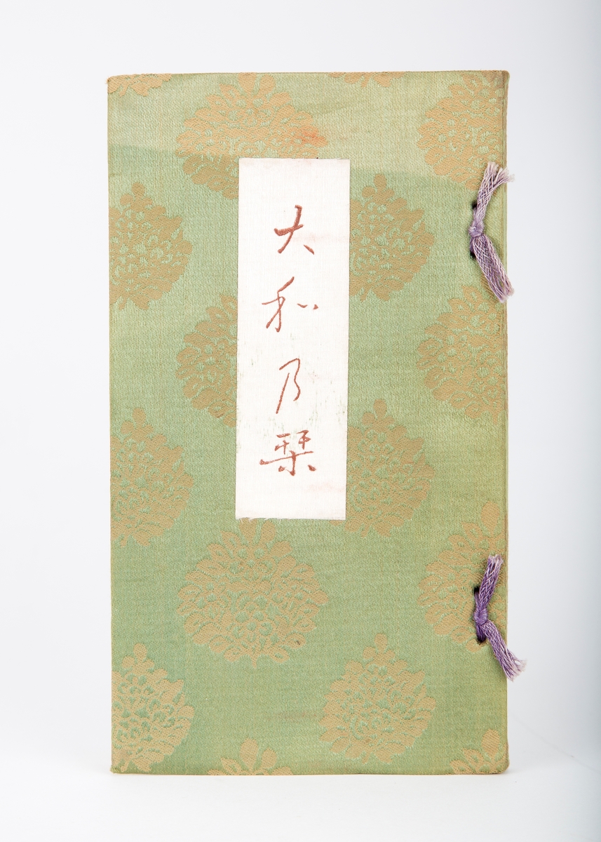 Bok. Grønt stoff, heftet, lilla bånd i rygg. Japansk.