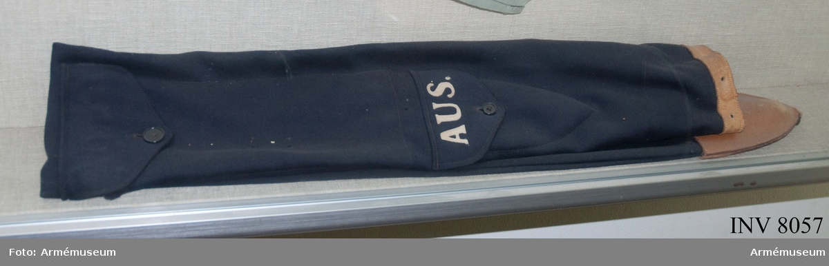 Fodral till fana AUS/AKS.
Fodral i mörkblått fint kläde med två fickor, en för kravatten och en för spetsen G V. På den understa fickan står AUS i vit applikation.